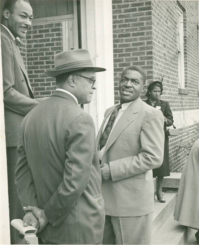 [Three Men Conversing on the Steps of a Building]