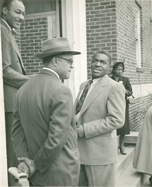 [Three Men Conversing on the Steps of a Building]