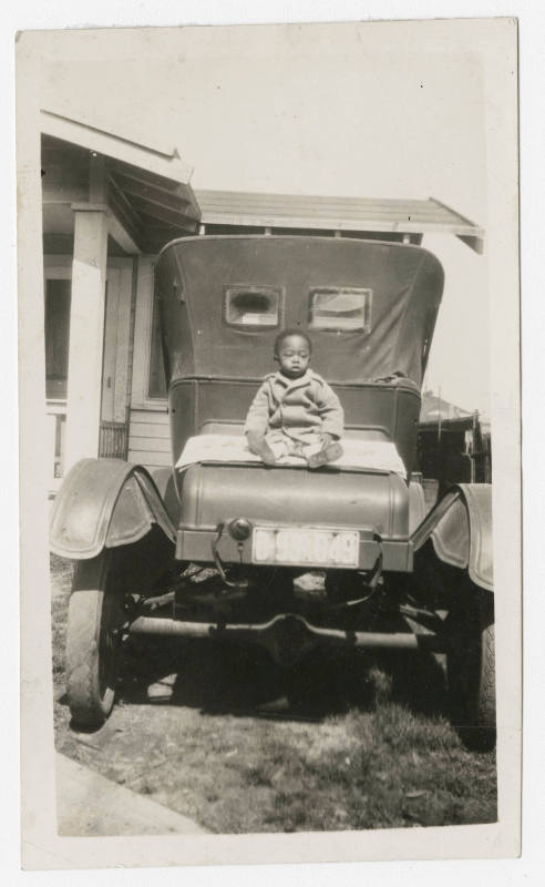 [Small boy sitting on a car]