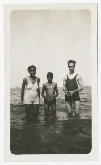 [Three people in swimsuits standing in water]