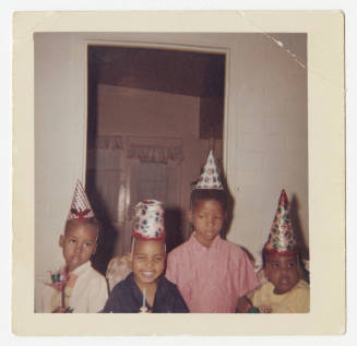 [Group of four boys wearing birthday hats]