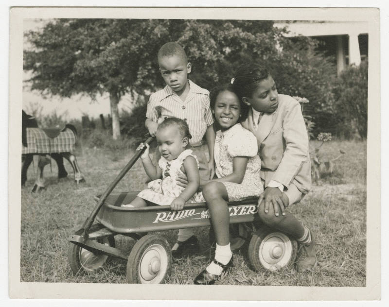 [Four children sitting in wagon]