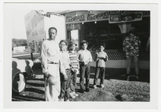[Man and boys standing in front of fireworks stand]