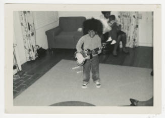 [Young boy playing a toy guitar]