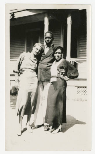 [Two women and a man standing in front of a house]