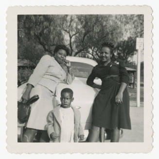 [Two women and a young boy standing in front of a car]