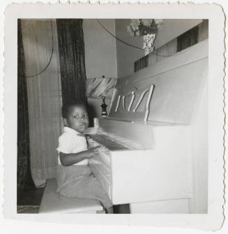 [Young boy sitting at a piano]