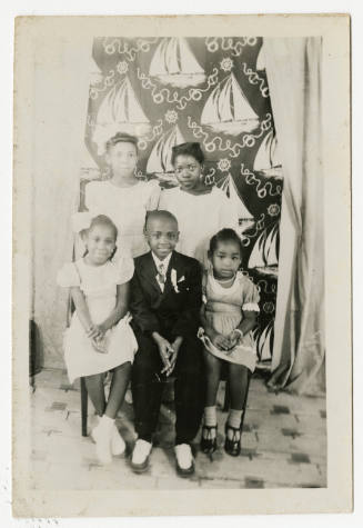 [Group of children seated in front of a backdrop]