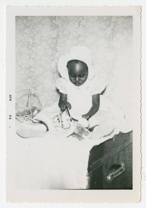 [Young girl sitting on trunk]