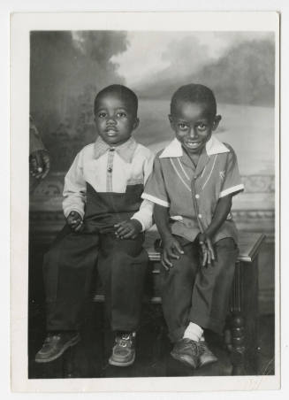 [Two boys seated in a studio]