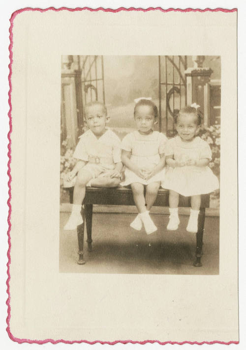 [Three young children seated in a studio]