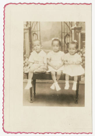 [Three young children seated in a studio]