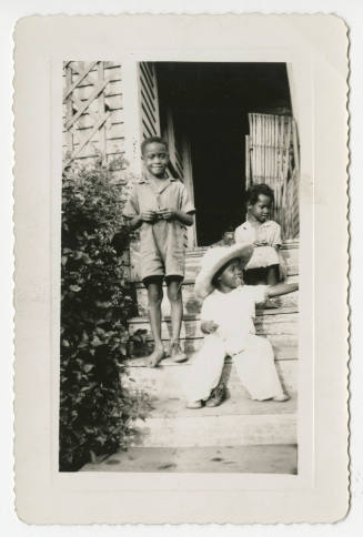 [Three children on the steps of a house]