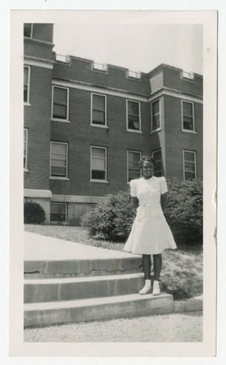 [Young woman standing in front of a building]