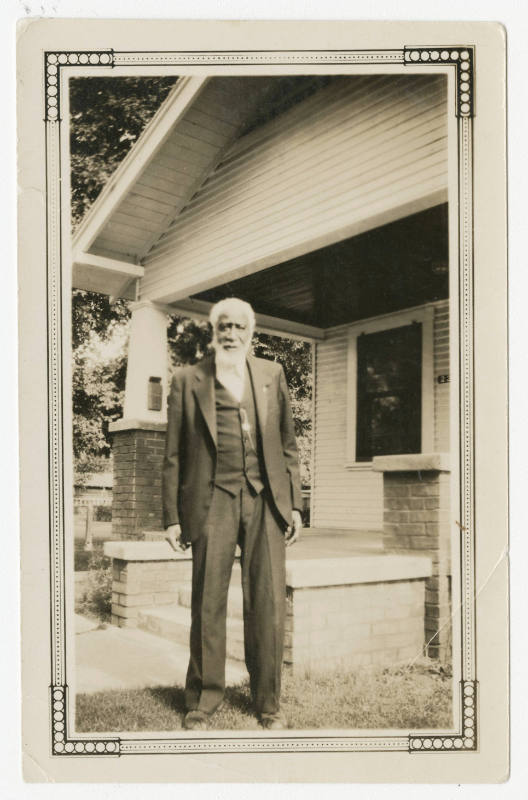 [Man standing in front of a house]