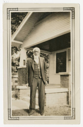 [Man standing in front of a house]