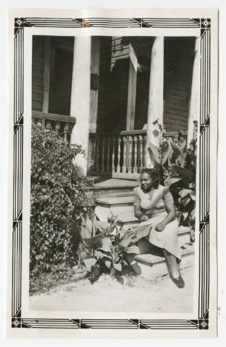 [Woman seated on house steps outside]