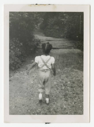[Young girl walking down a forest trail]