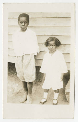 [Young boy and girl standing in front of a building]