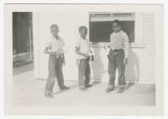 [Three boys in front of a house with toy guns]
