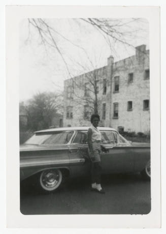 [Young woman standing in front of a car]