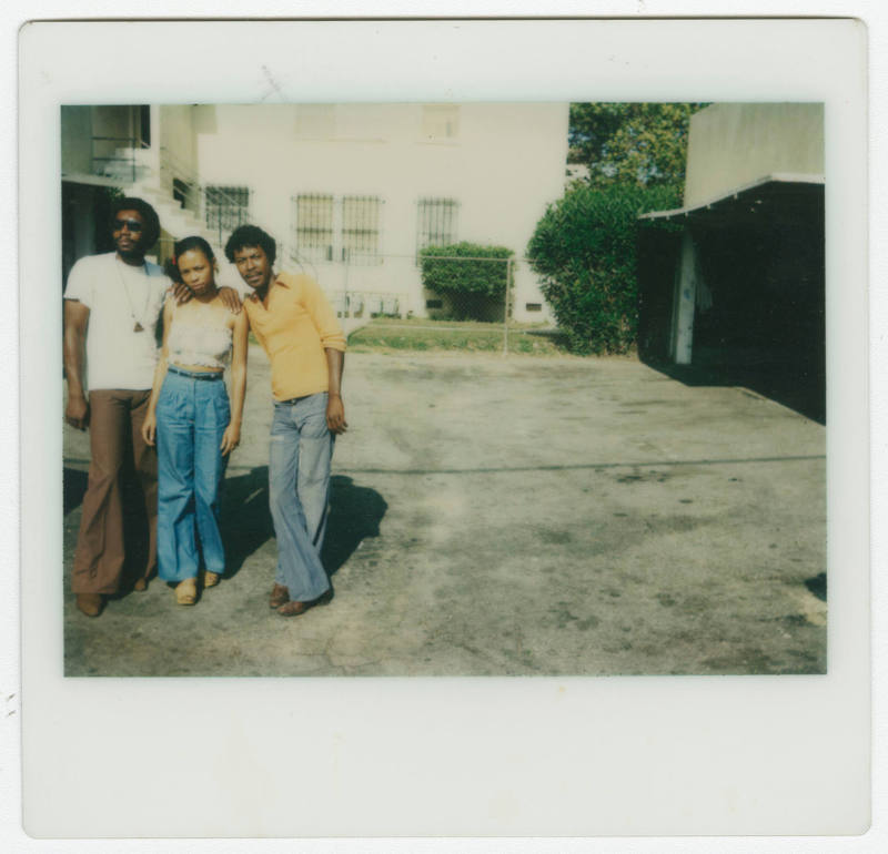 [Two men and a young woman standing outside]