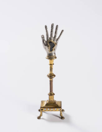 A repousséd silver hand reliquary raised on a gilded copper stand