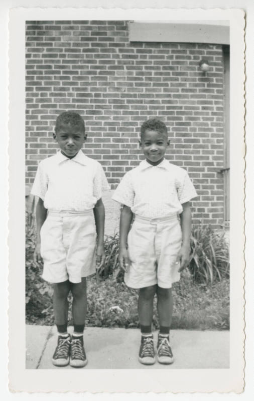 [Two boys in matching outfits standing outside]