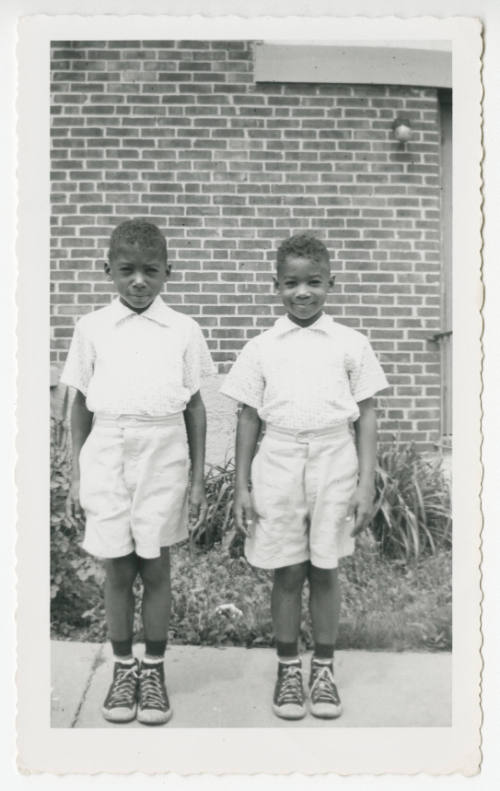 [Two boys in matching outfits standing outside]