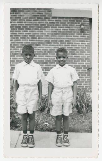 [Two boys in matching outfits standing outside]