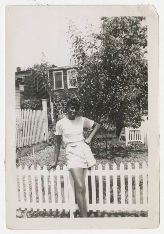 [Woman standing outside next to fence]