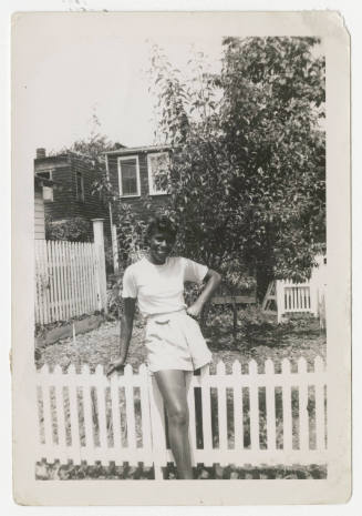 [Woman standing outside next to fence]