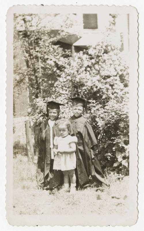 [Three children standing outdoors]