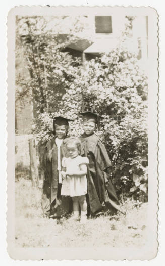 [Three children standing outdoors]