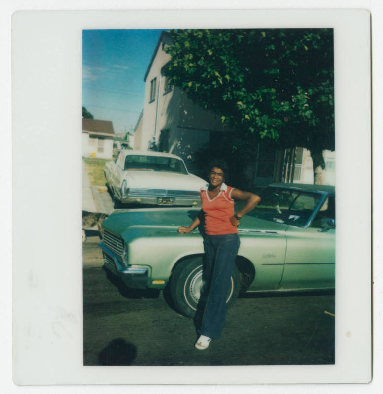[Young woman leaning against a Buick LeSabre]